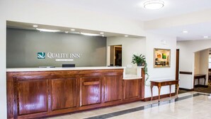 A reception desk with a wooden finish and a sign reading "Quality Inn by Choice Hotels". - Quality Inn Fuquay Varina East (Fuquay-Varina)