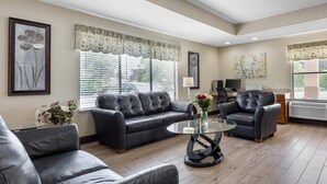 A living room with a leather sofa, a glass coffee table, and a black armchair. - Quality Inn Fuquay Varina East (Fuquay-Varina)