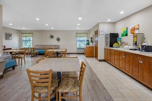 A spacious kitchen with wooden cabinets, a dining area with a table and chairs, and a kitchenette with a refrigerator and coffee maker.