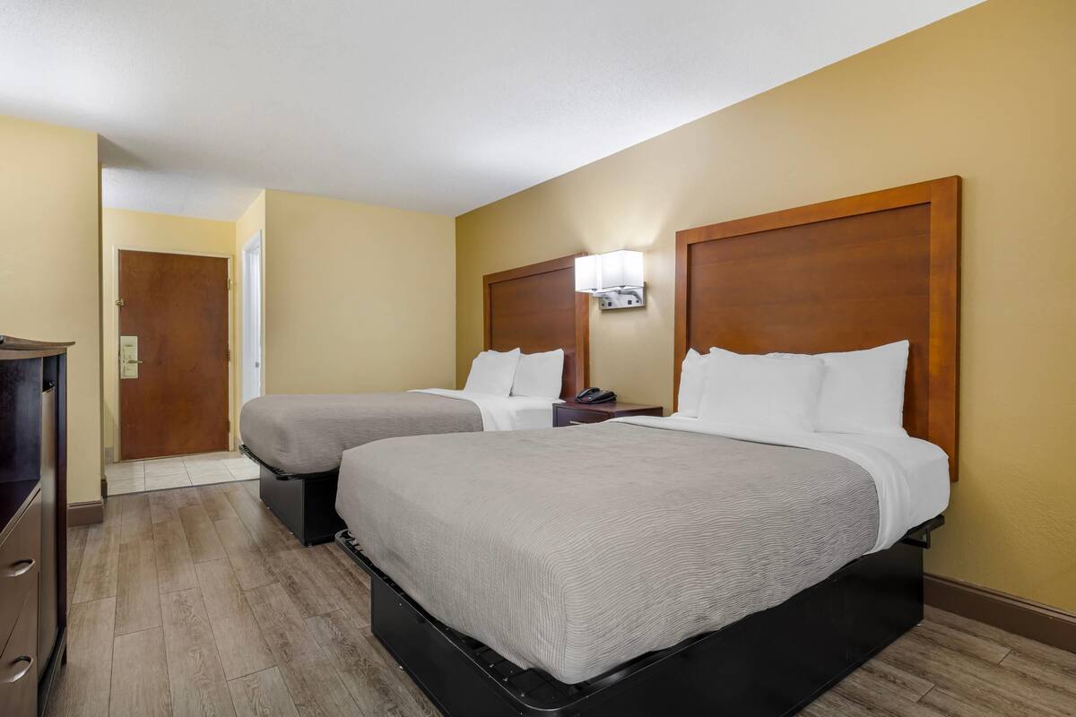 A hotel room with two beds, a desk, and a wardrobe.