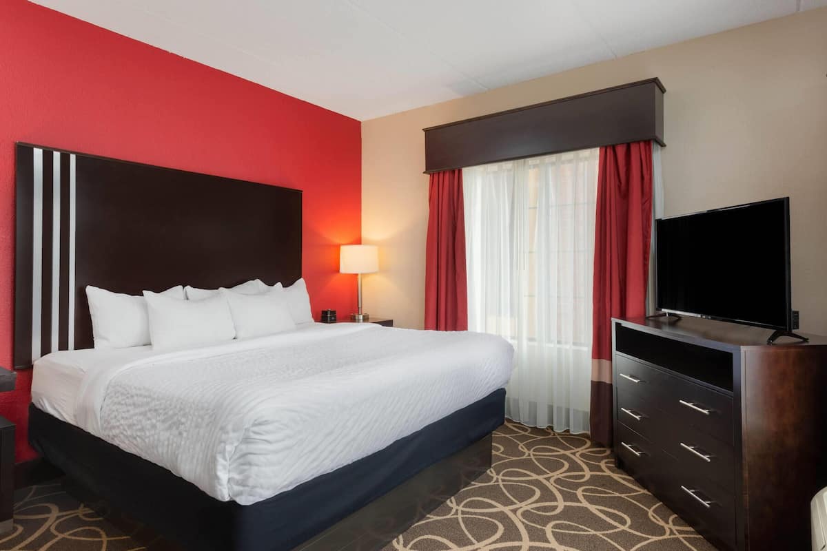 Een hotelkamer met een groot bed, een televisie, een nachtkastje en een lamp.
