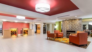 Un vestíbulo moderno con mostrador de recepción, zona de estar y chimenea.