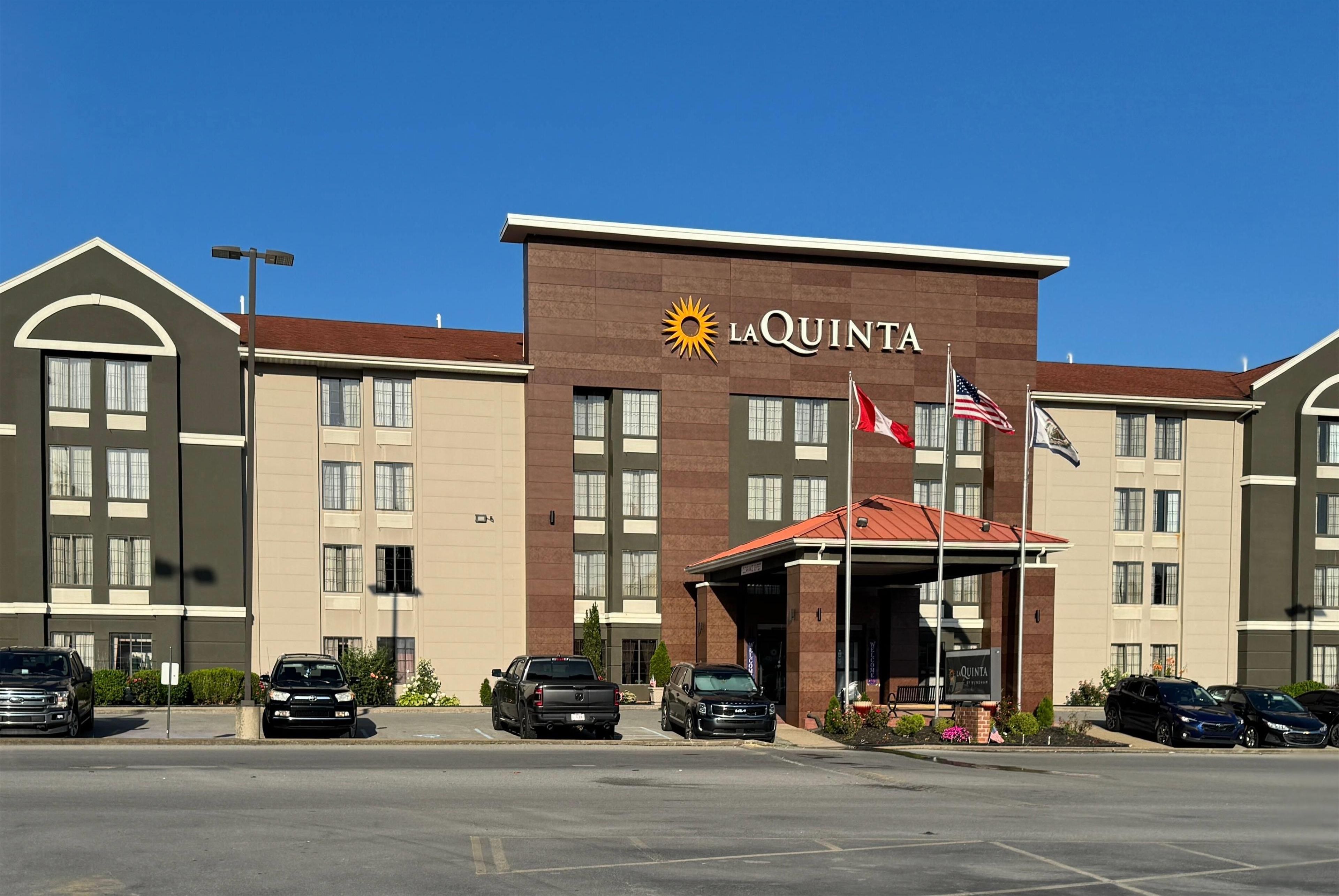 A La Quinta hotel with a brown facade, multiple windows, and a parking lot with several cars.
