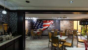A restaurant with a large American flag mural on the wall, wooden flooring, and a mix of table and booth seating.