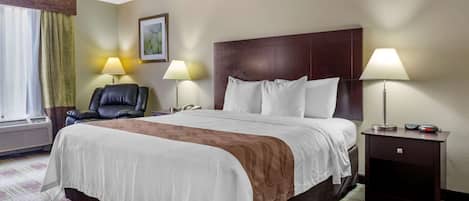 Una habitación de hotel con una cama grande, dos lámparas de noche, un sillón de cuero y una mesita de noche con un reloj.