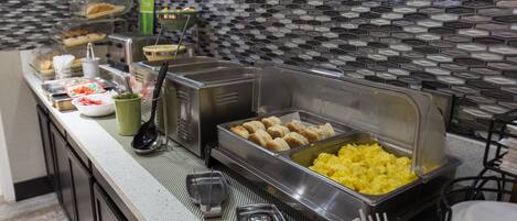 A buffet setup with various food items and serving utensils.