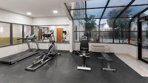 Une salle de sport équipée de tapis de course, d’un appareil elliptique et d’un banc de musculation.