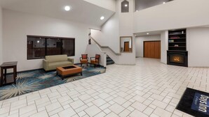 Un vaste espace de vie comprenant un escalier, un canapé, des fauteuils, une cheminée et une bibliothèque.