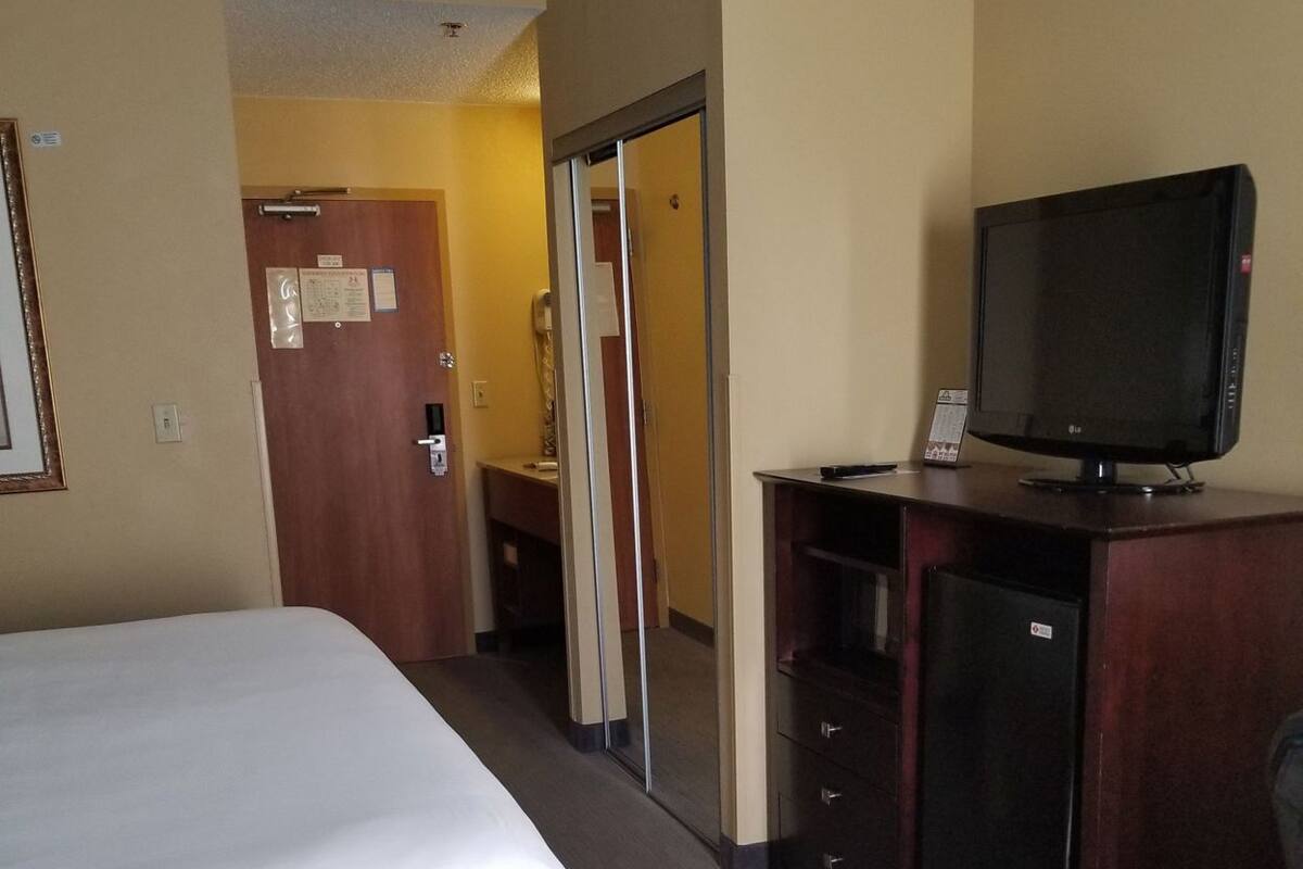 Une chambre d’hôtel équipée d’un lit, d’une télévision, d’un bureau et d’un miroir.