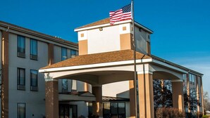 A modern hotel entrance with a covered driveway, an American flag, and a building with large windows.