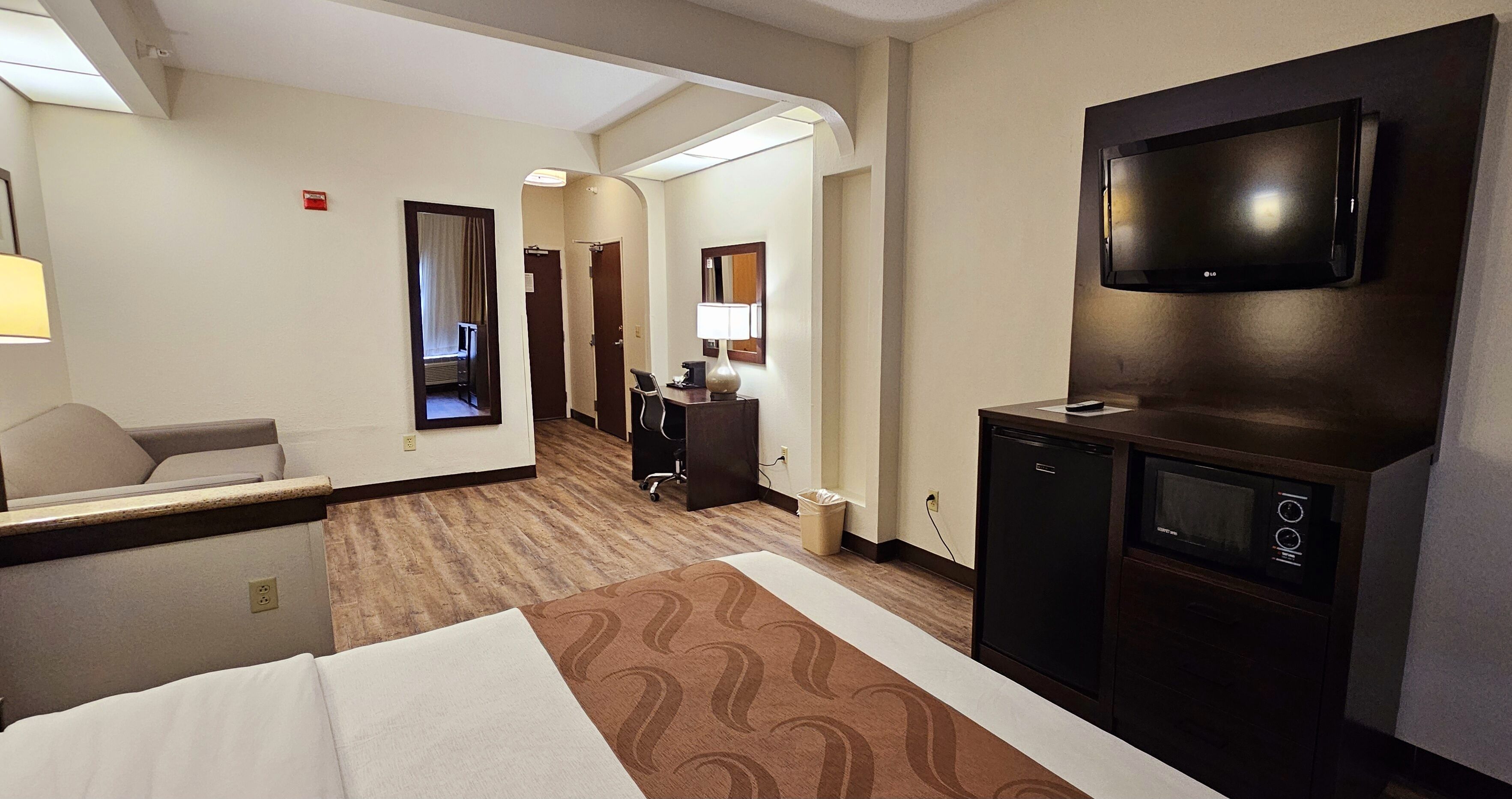 Een hotelkamer met een bed, een bureau, een televisie en een minibar.