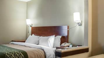 Una habitación de hotel con cama, mesita de noche, lámpara y teléfono.