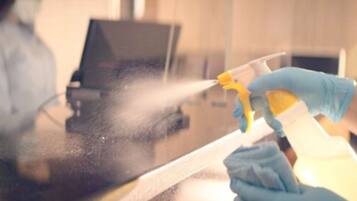 A person cleaning a glass surface with a spray bottle.