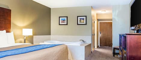 Habitación de hotel con una cama grande, baño independiente con bañera, escritorio y televisión.