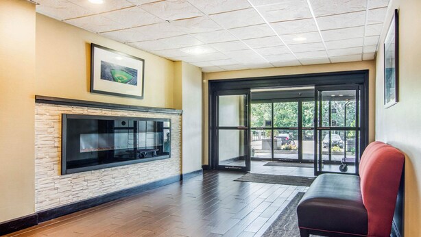 A lobby with a stone wall, a fireplace, a bench, and a glass door leading outside. - Comfort Inn Atlanta Downtown South (Atlanta)