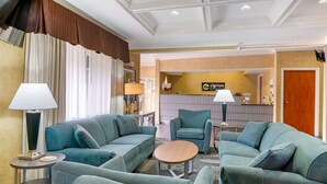 Un vestíbulo de hotel con sofás color turquesa, una mesa redonda de madera y una recepción.