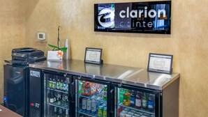 Un área de recepción con un refrigerador lleno de bebidas, una impresora y un televisor mostrando el logotipo de Clarion Pointe.