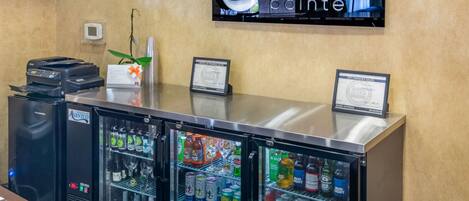 A reception area with a refrigerator stocked with beverages, a printer, and a television displaying the Clarion Pointe logo.