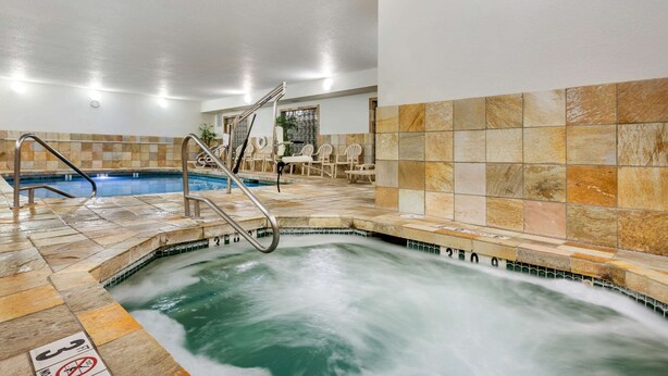 Zona de hidromasaje con suelo de baldosas, una escalera metálica y una piscina.