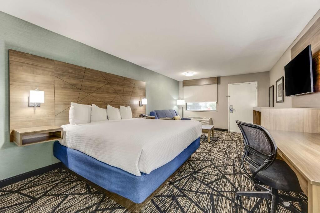Een hotelkamer met een groot bed, een bureau, een stoel, een televisie en een raam.