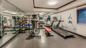 A gym with weightlifting equipment, treadmills, and a mirrored wall. - Clarion Pointe (Huntsville)
