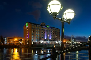 A hotel with a large building, a waterfront, and a bridge.
