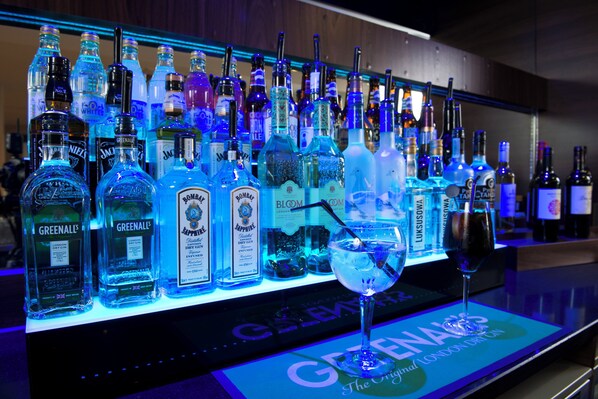 Un bar con una variedad de botellas de licor y una copa de ginebra en la barra.