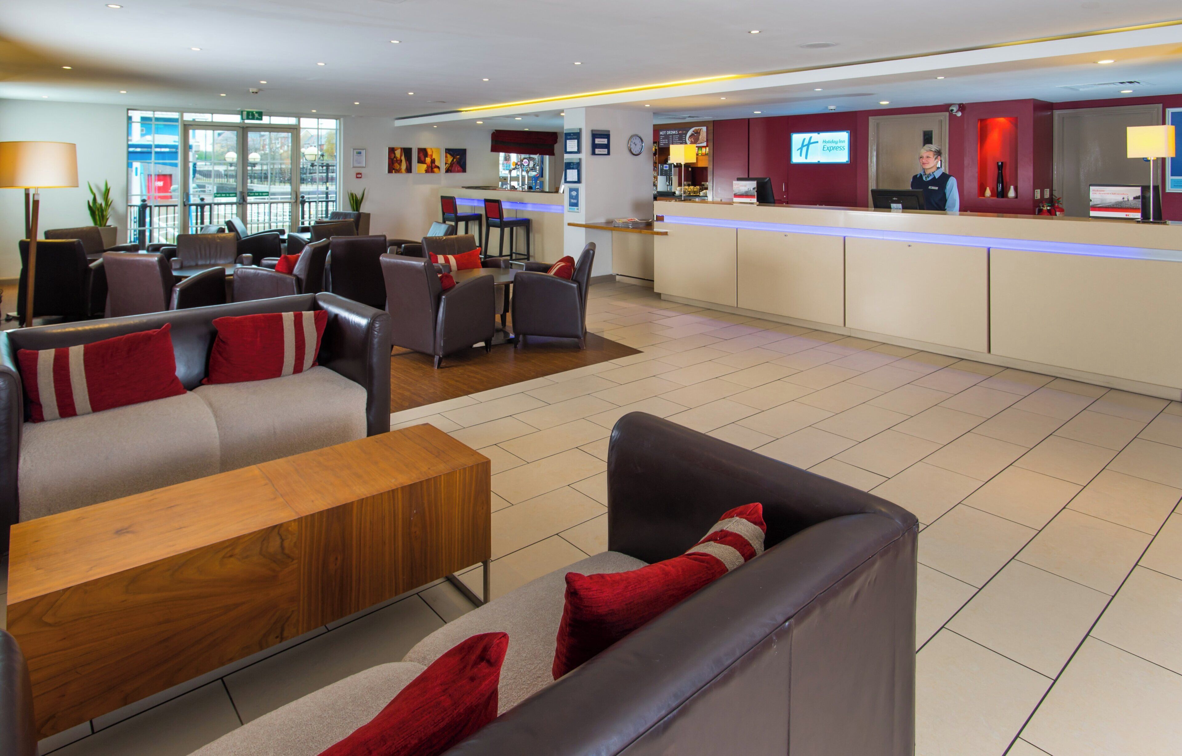 A hotel lobby with seating areas, a reception desk, and a view of the outside.