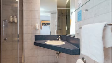 A modern bathroom with a glass-enclosed shower, a sink with a dark countertop, and a towel rack.