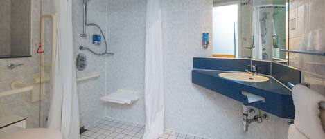 Un baño con ducha, inodoro, lavabo y espejo.