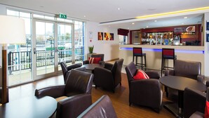Et moderne loungeområde med læderpolstrede møbler, en bar og store vinduer med udsigt over byen.