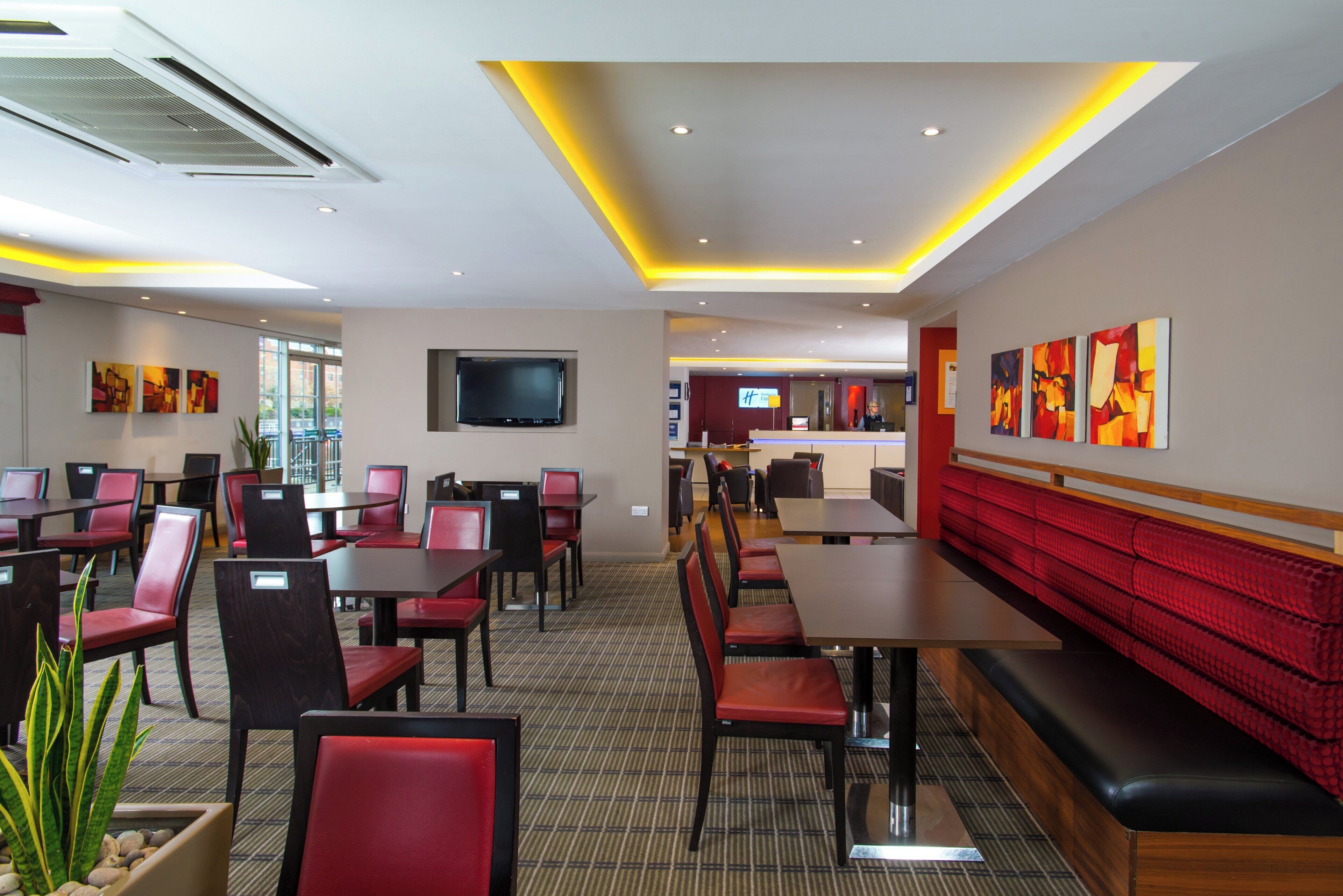 Un restaurante con cabinas y mesas, un televisor de pantalla plana en la pared y obras de arte decorando las paredes.