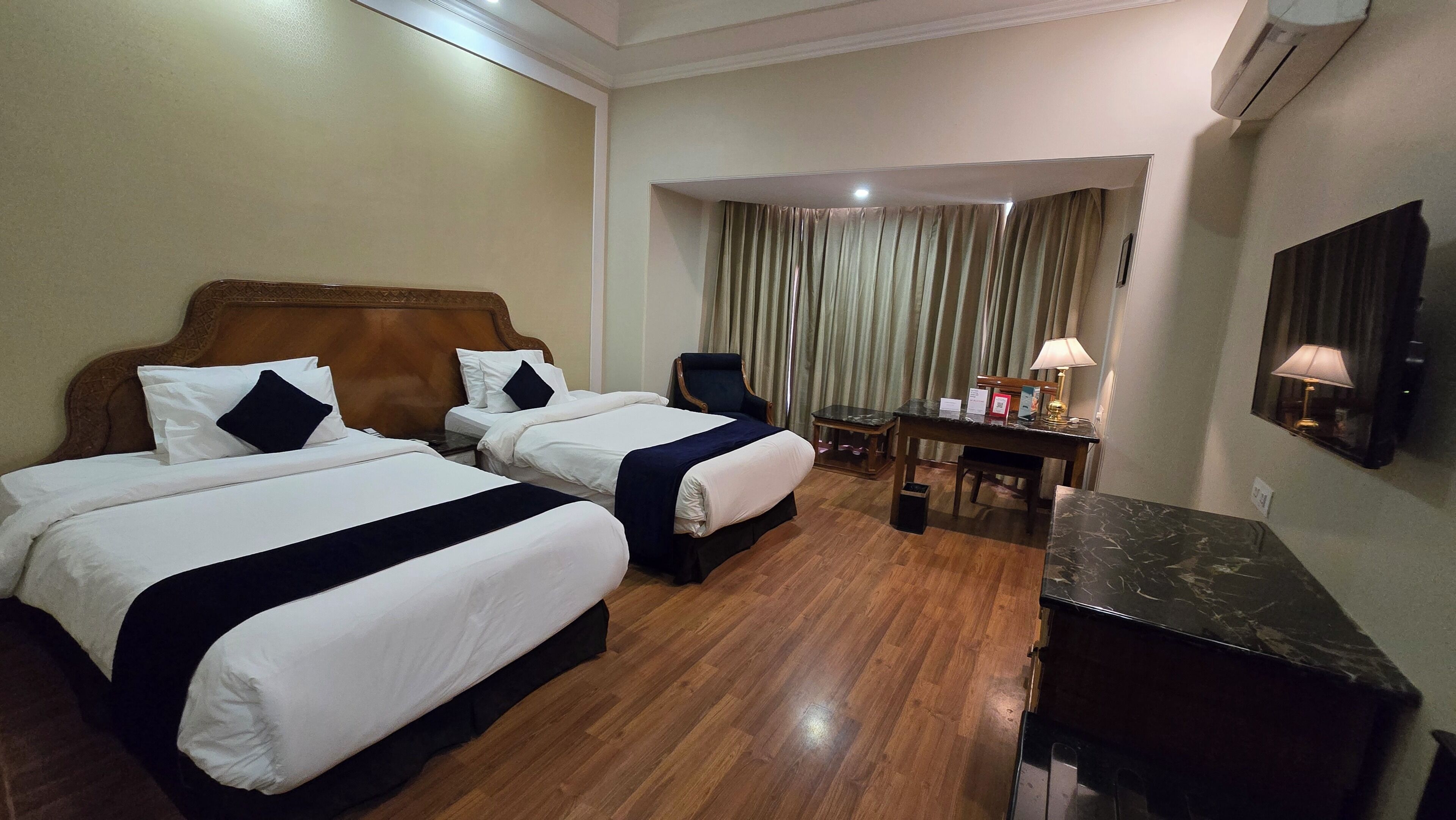 Une chambre d’hôtel avec deux lits, un bureau, une chaise, une lampe et un miroir.