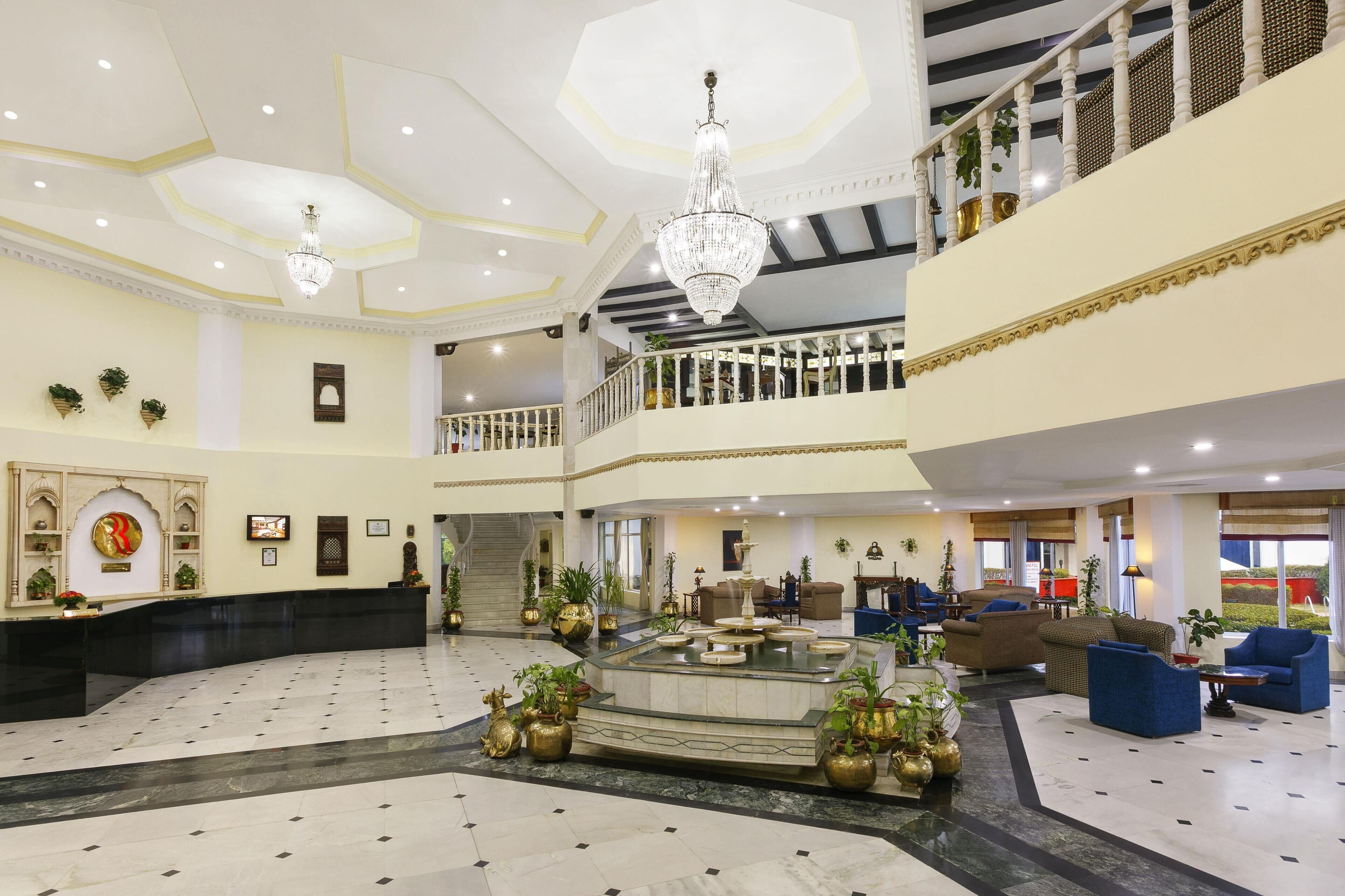 A spacious lobby with a central fountain, multiple seating areas, and a staircase leading to an upper level.