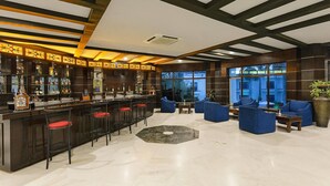 Zona de bar con taburetes, barra y una sala de estar con sofás y una mesa de centro.