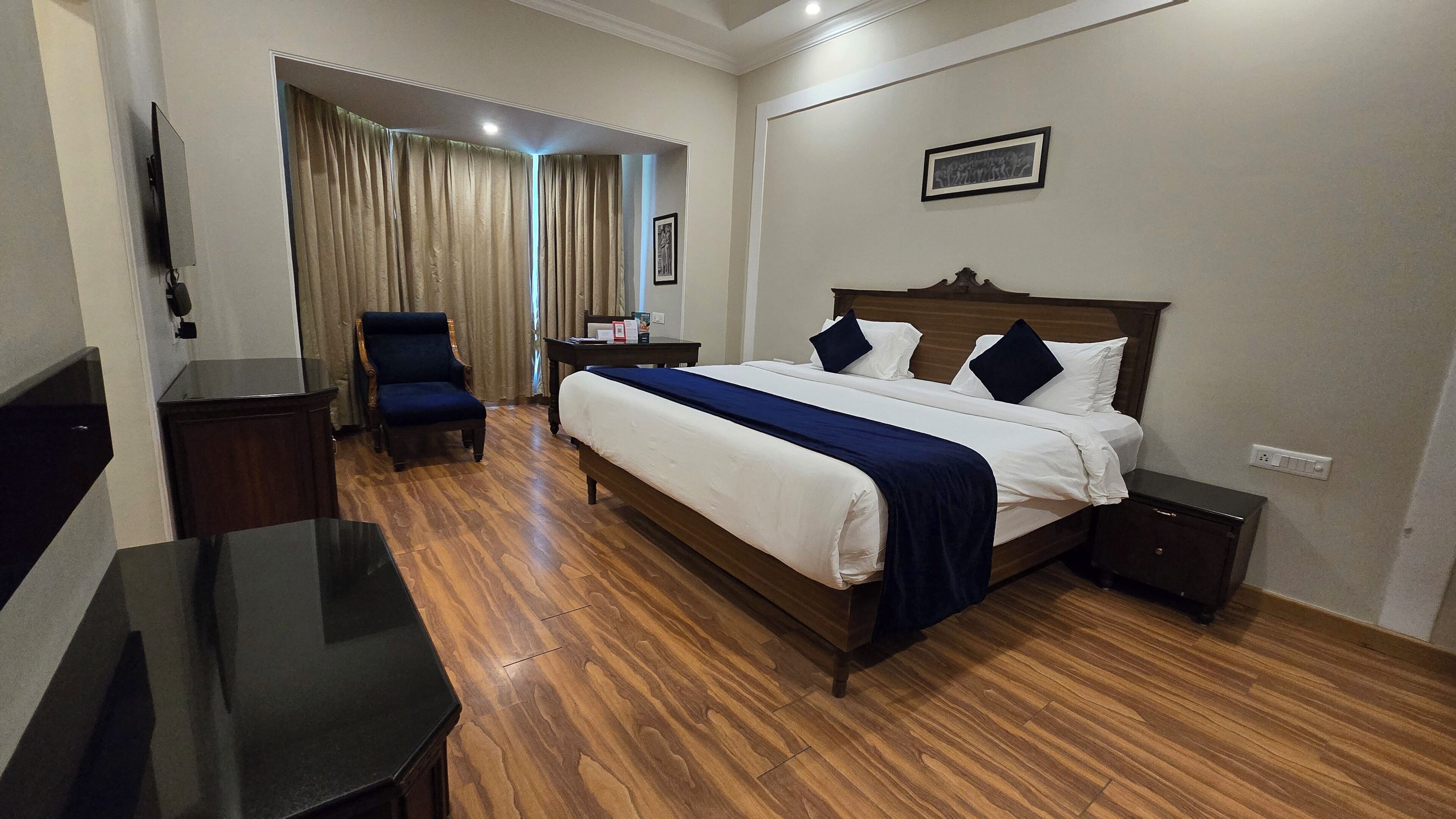 A hotel room with a bed, a chair, a desk, and a television.