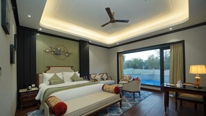 Un dormitorio con cama, zona de estar, escritorio y vistas al exterior.
