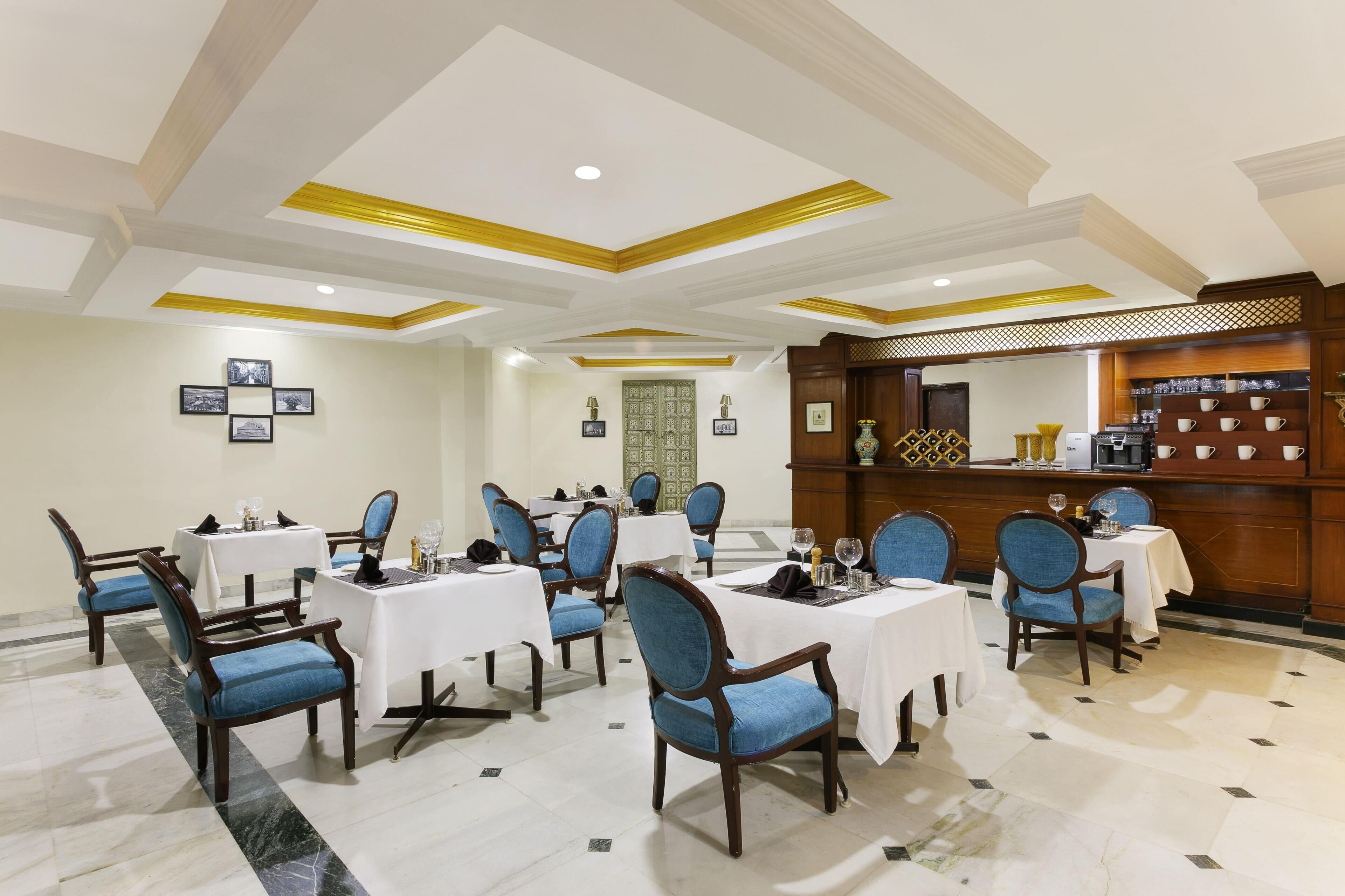A hotel dining area with tables and chairs, a reception desk, and framed pictures on the walls.