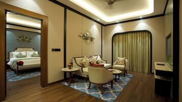 Una habitación de hotel con cama, zona de estar, televisor y espejo.