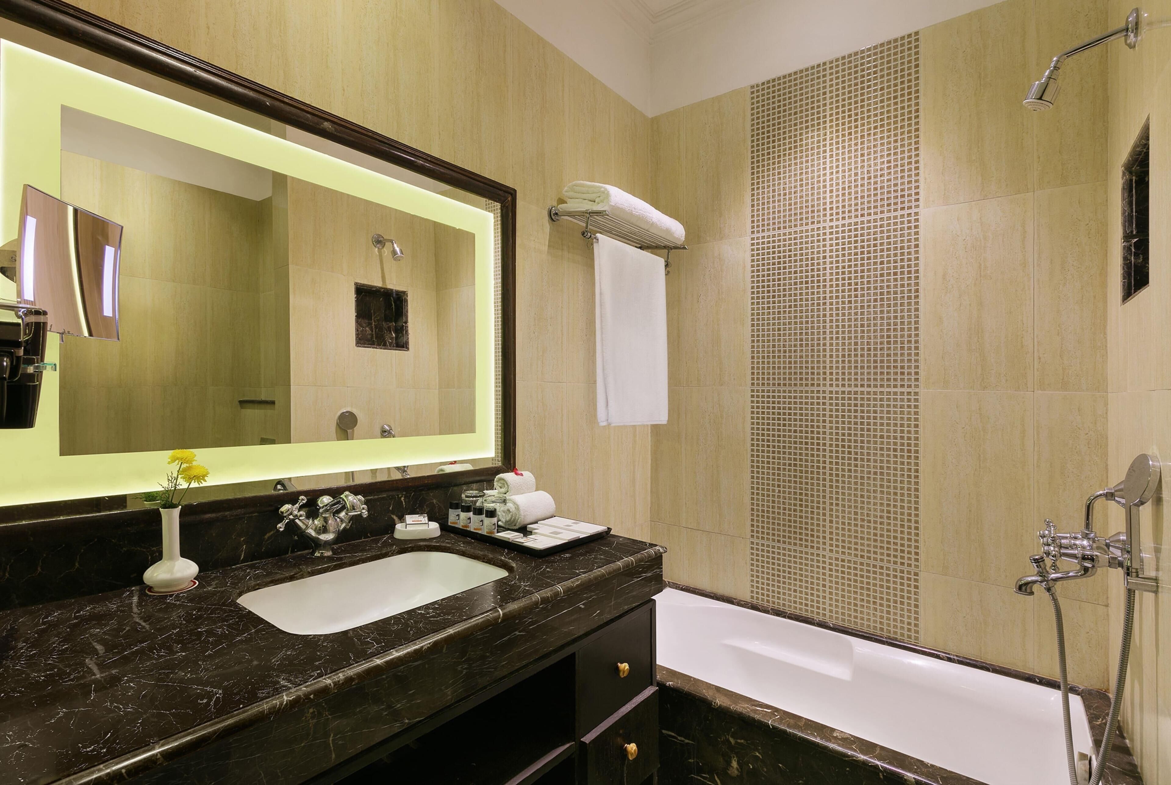 Une salle de bain avec un grand miroir, un lavabo, une baignoire et une douche.