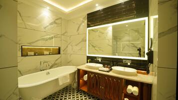 Un baño moderno con una bañera independiente, dos lavabos, un espejo grande y paredes de mármol.