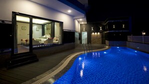 Piscina con cerramiento de vidrio y zona de descanso con asientos.