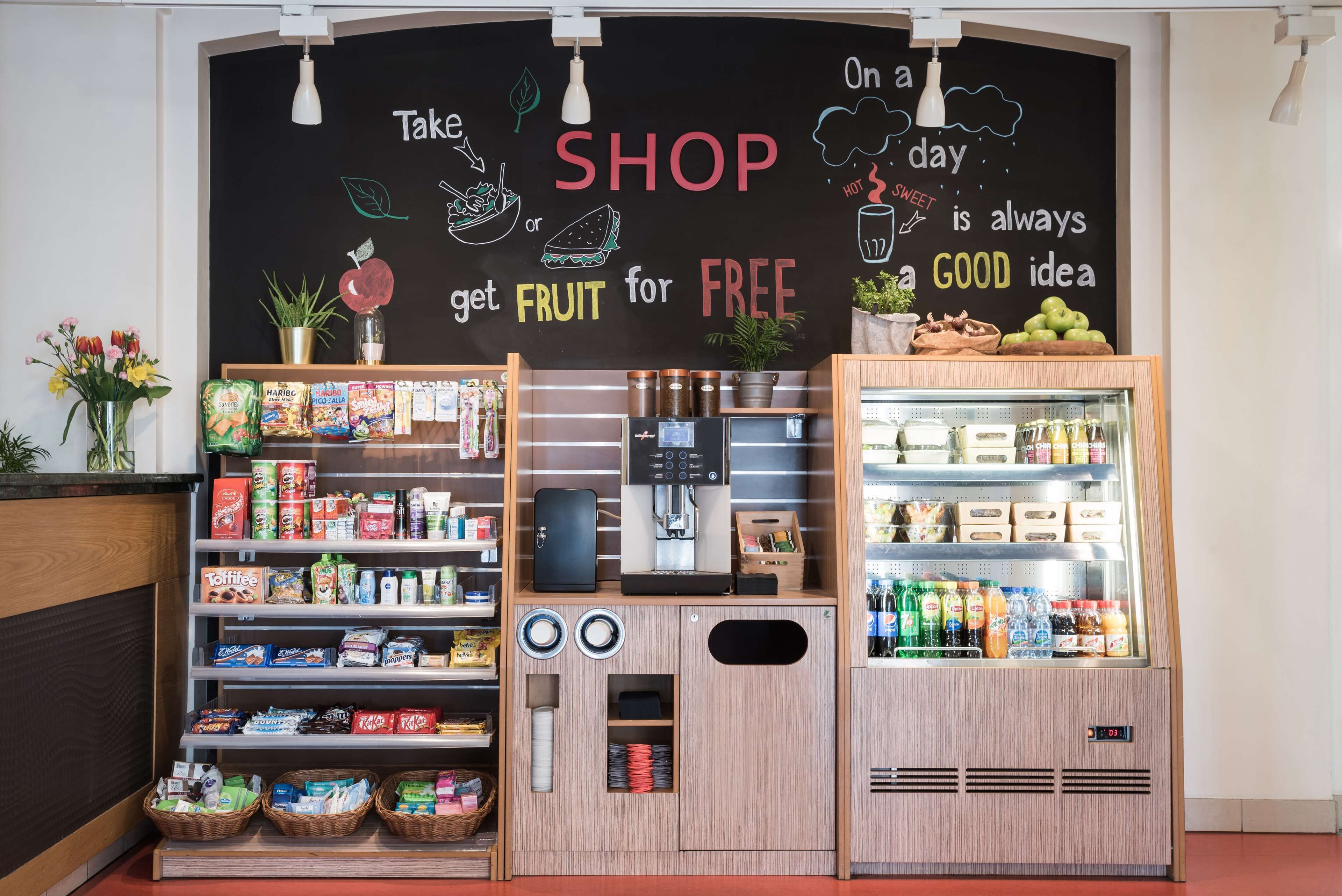 En butik med et skilt, der siger "Tag frugt gratis", og en kaffemaskine.