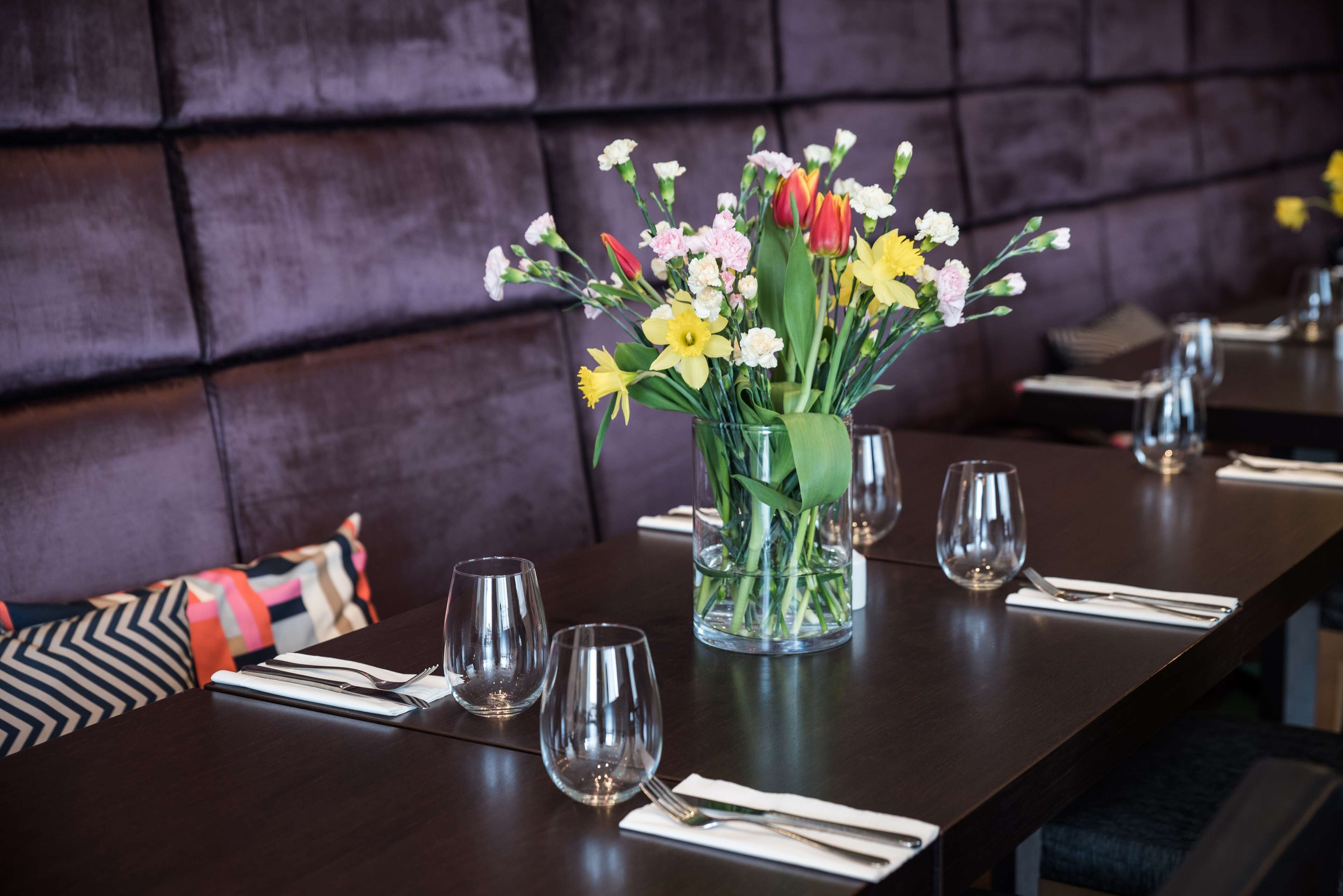Une table à manger dressée avec plusieurs verres à vin et un vase rempli de fleurs.