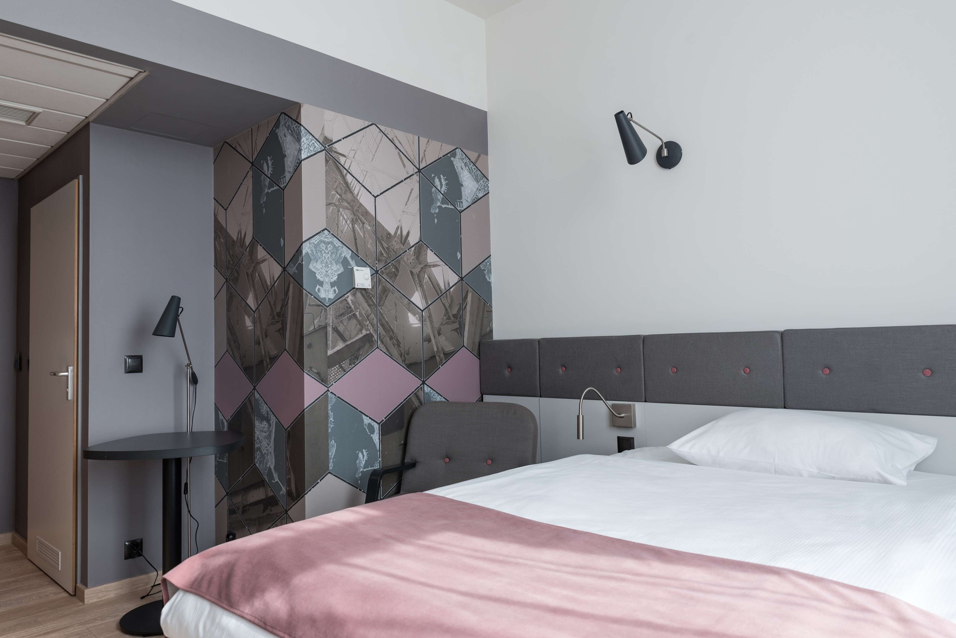Een moderne hotelkamer met een bed, een bureau en een stoel.