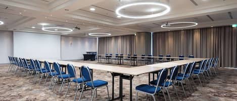 A conference room with a long table, blue chairs, and a carpeted floor.