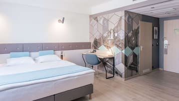 Ett modernt hotellrum med en säng, ett skrivbord och en stol.