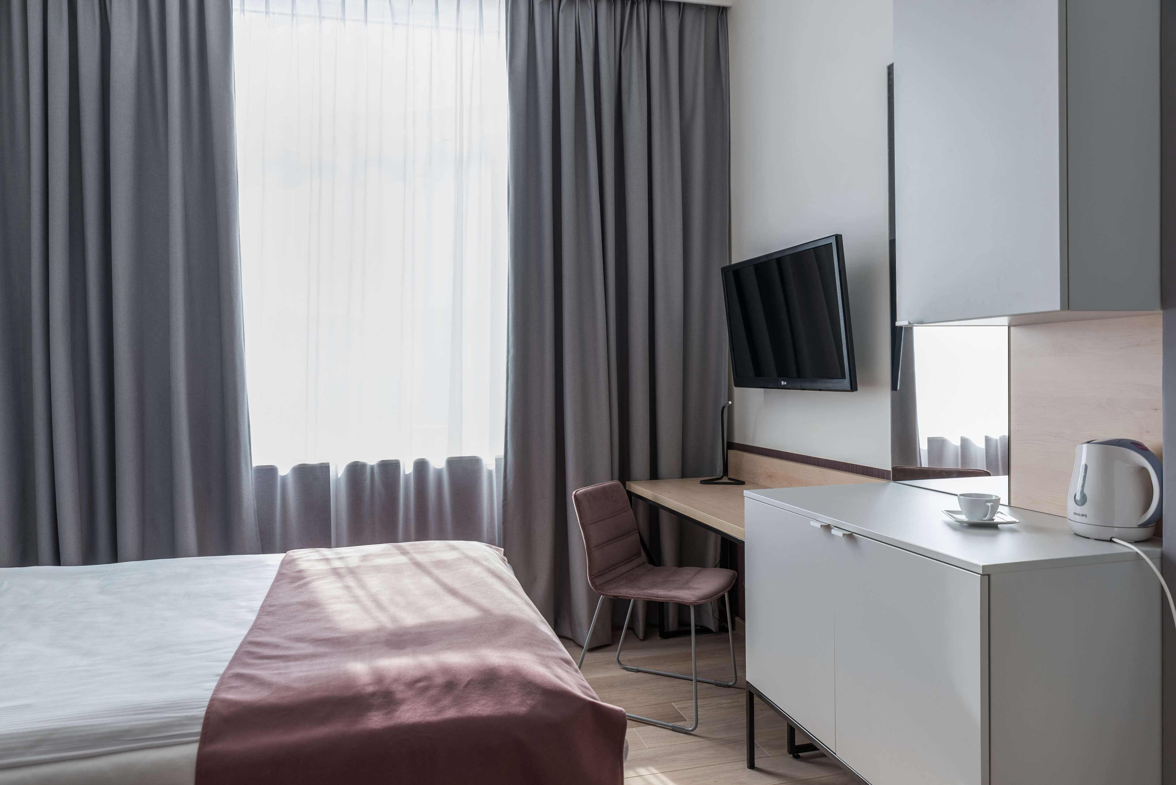 Habitación de hotel con cama, escritorio, silla, televisión y armario.