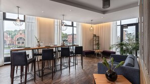 Un comedor moderno con barra, asientos y amplios ventanales que ofrecen vistas a edificios y zonas verdes.
