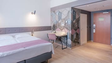 Een hotelkamer met een bed, bureau, stoel en een muur met een geometrisch patroon.